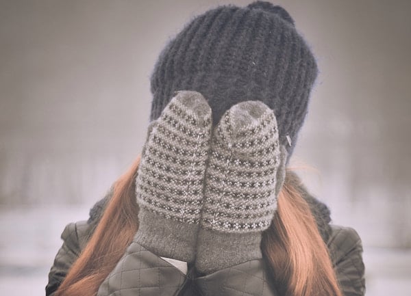 girl covers face with hands in the cold