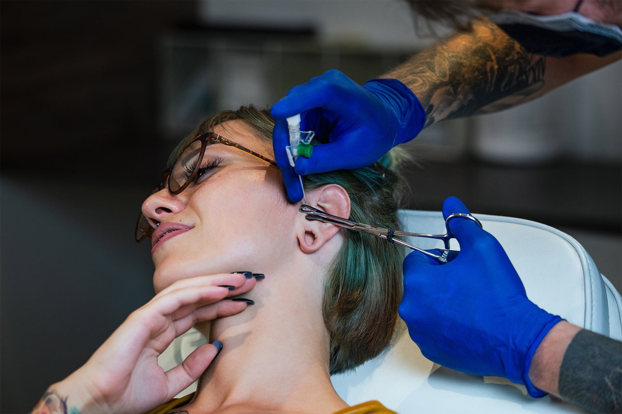 piercer piercing a woman's ear