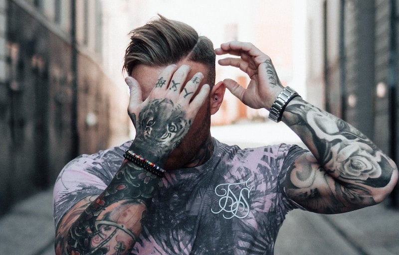 tattooed man covers face