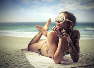 Tattooed girl sunbathing on the beach