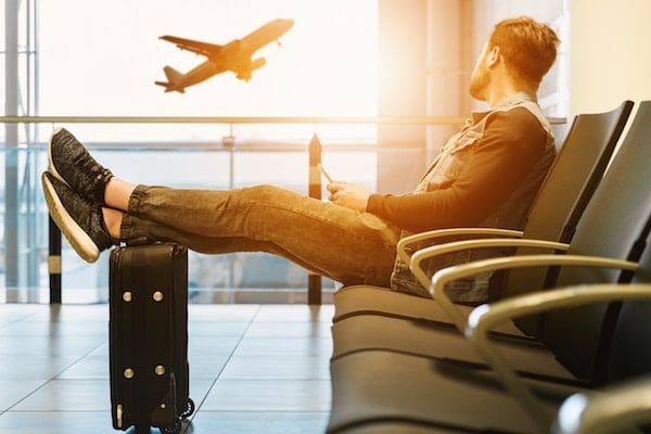 man sits in airport and watches plane