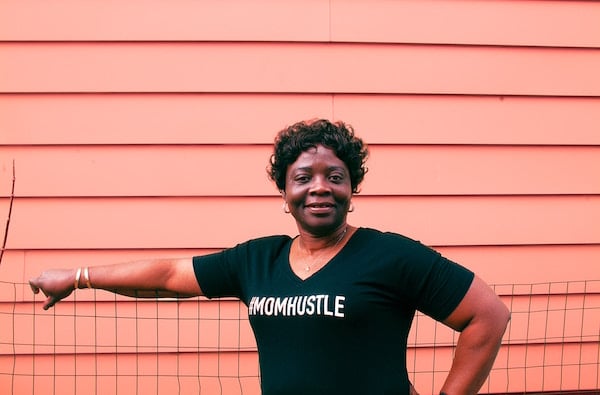 mom with #momhustle shirt stands by fence