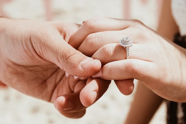 man holds woman's hand with engagement ring