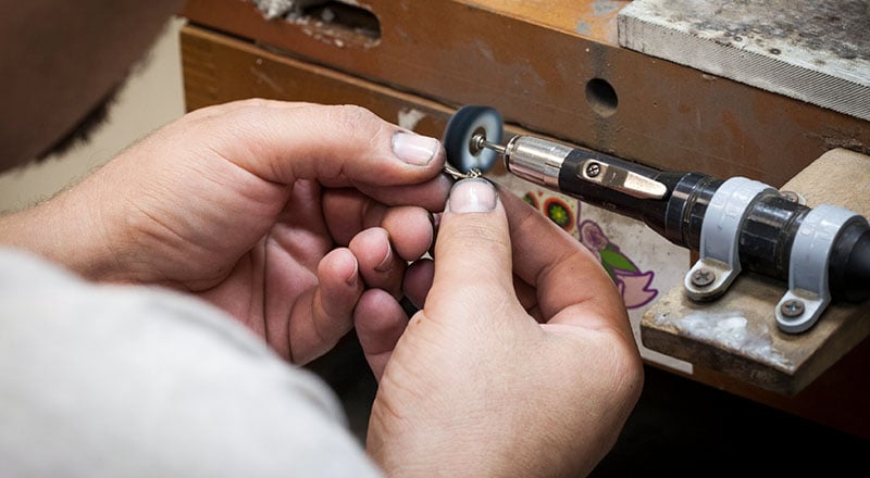 Close up of man polishing belly ring