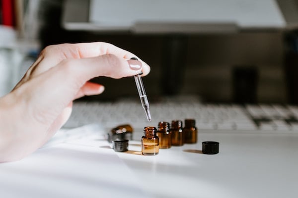 a hand drips tea tree oil from a dropper