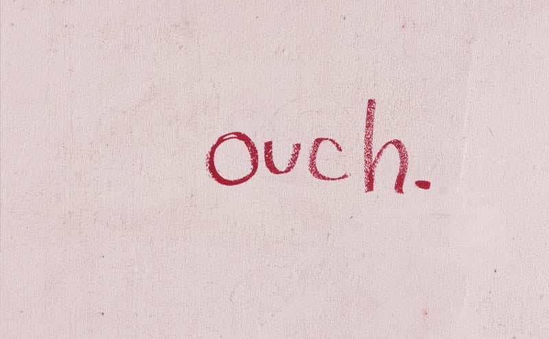 "Ouch" written on a wall in red lipstick