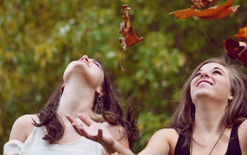 two women throwing leaves in the air