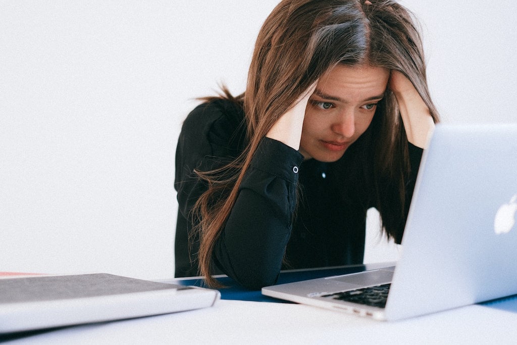 woman looking stressed while looking at laptop