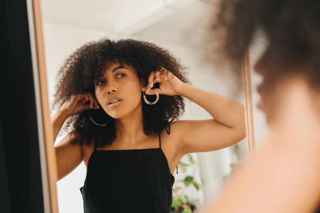 Woman Looking at Earrings in Mirror