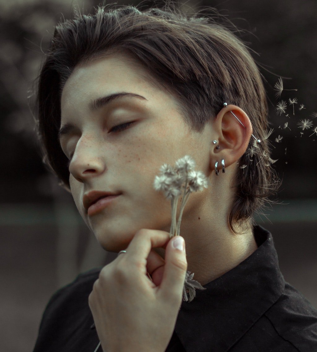 Woman Holding a Flower with Multiple Piercings