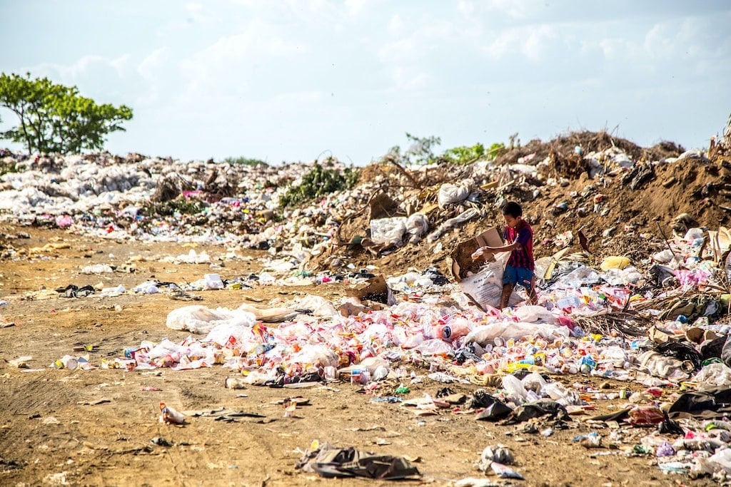 young waste picker in mismanaged landfill